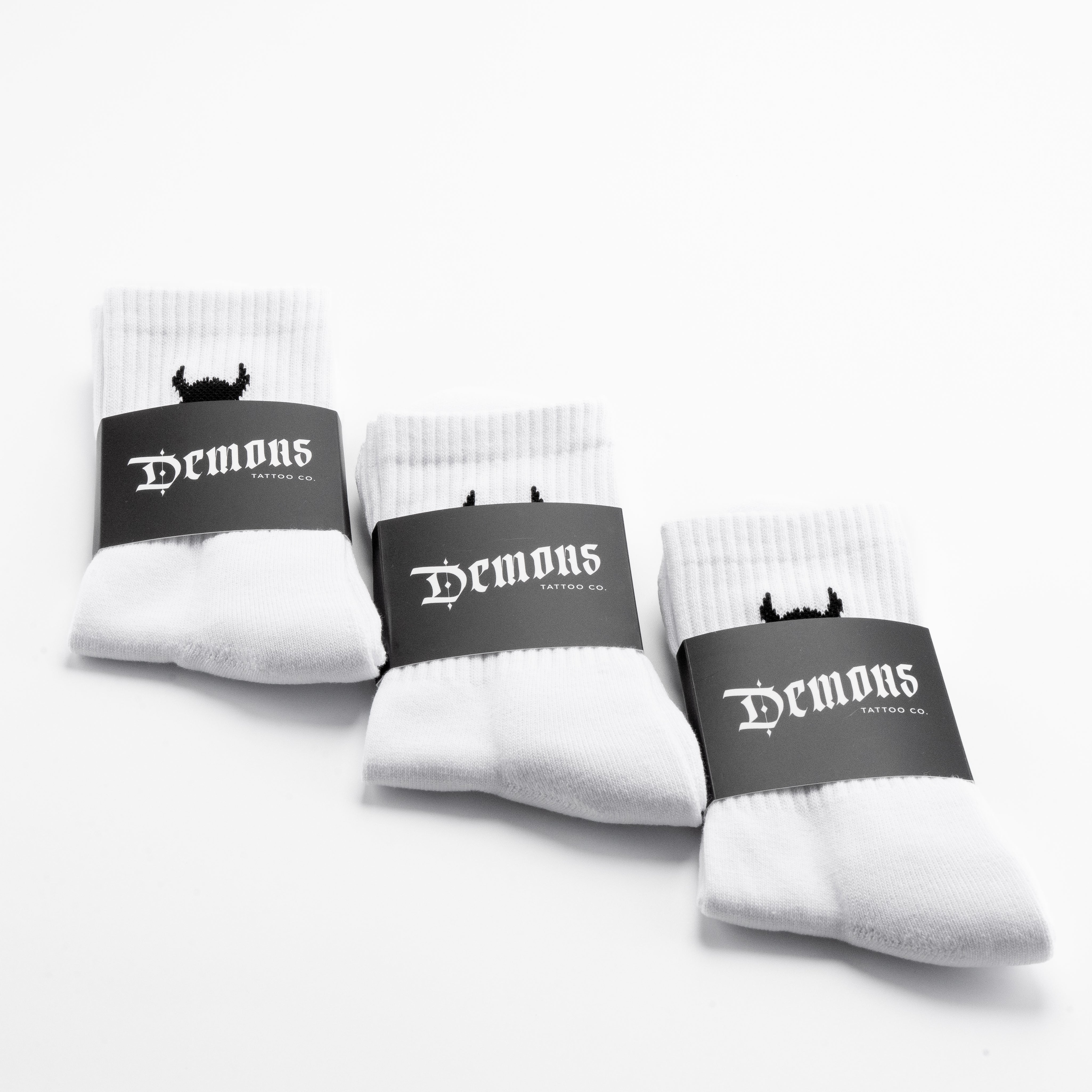 Three pairs of white Demons crew socks in their branded paper bands