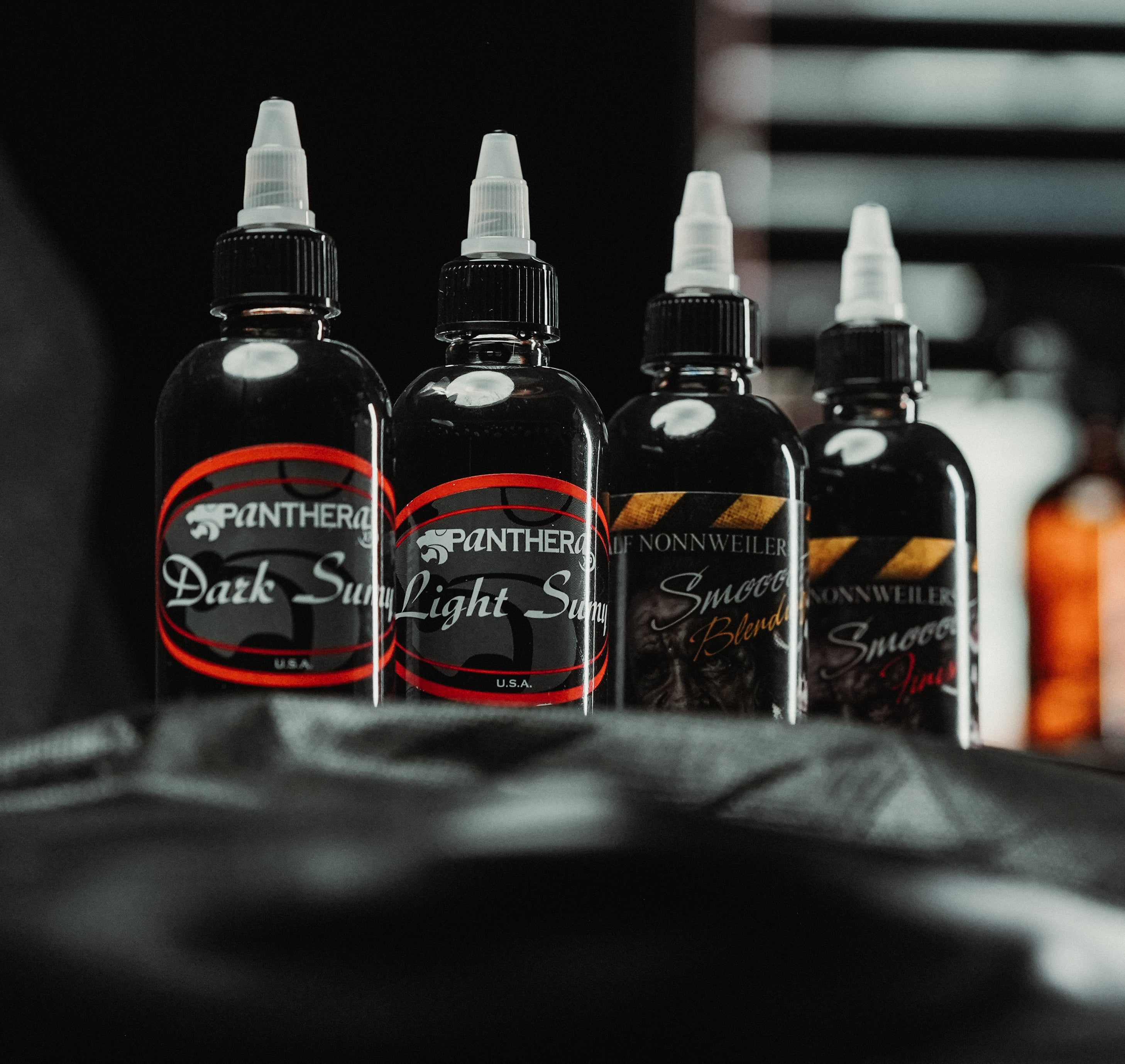 The four Panthera grey wash bottles on a tattoo artist's workstation, low-light studio shot