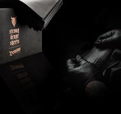 Gloved hand taking a black drape sheet from the Demons Strong box in a dark studio
