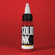 Solid Ink Super Red tattoo ink 2 oz bottle on coloured background