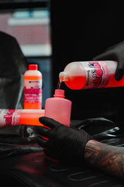 Gloved hand pouring pink Panthera Babool soap into a studio wash bottle