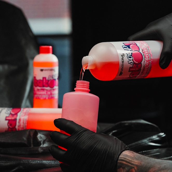 Gloved hand pouring pink Panthera Babool soap into a studio wash bottle