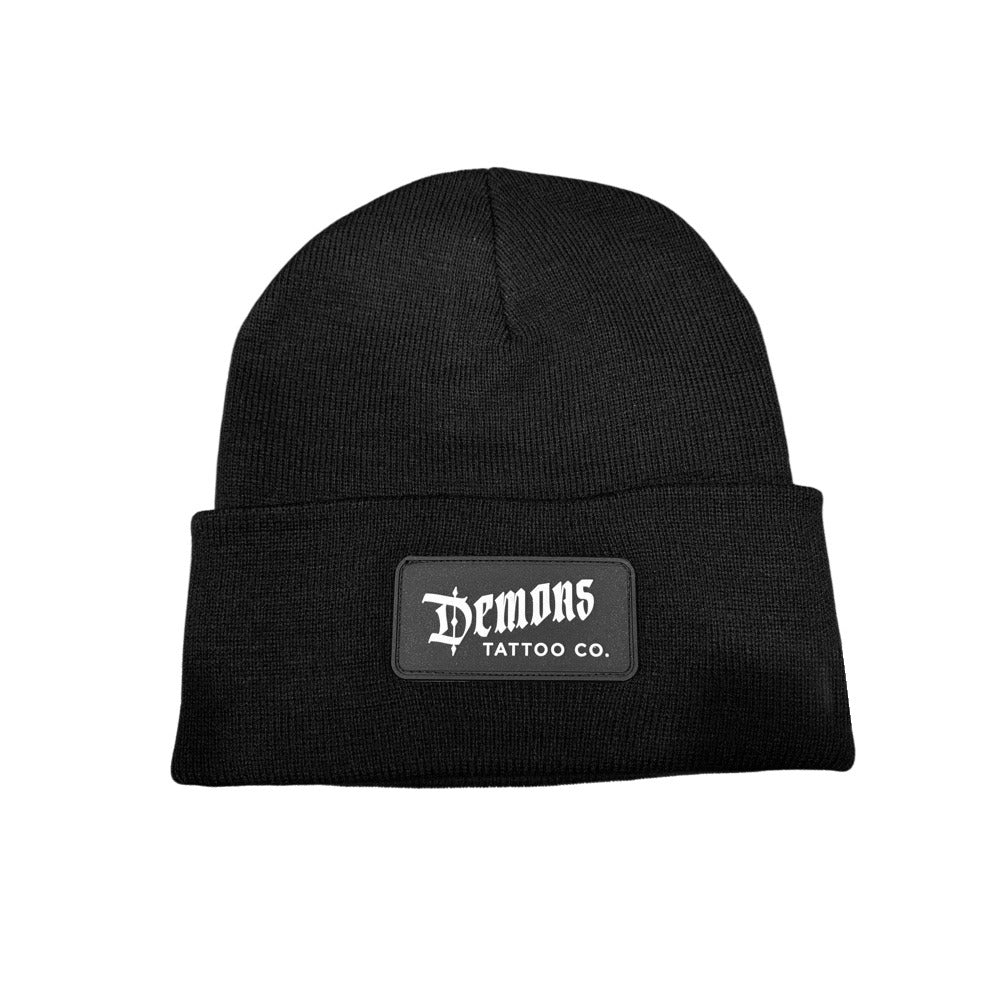 Black cuffed Demons beanie with a black PVC patch on the cuff, DEMONS in white gothic lettering above TATTOO CO.
