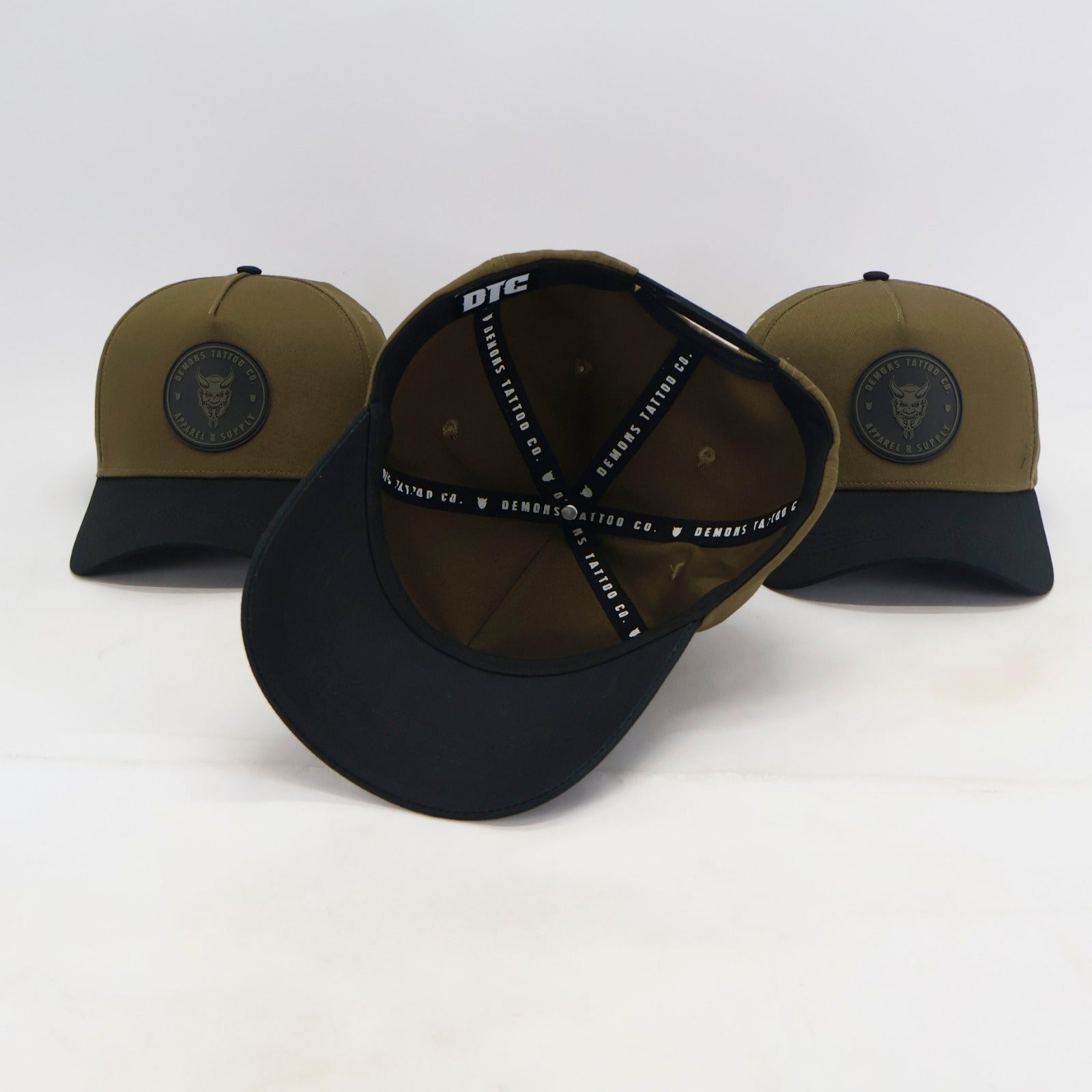 Intérieur de la snapback Demons olive avec le ruban noir DEMONS TATTOO CO. et l'étiquette DTC