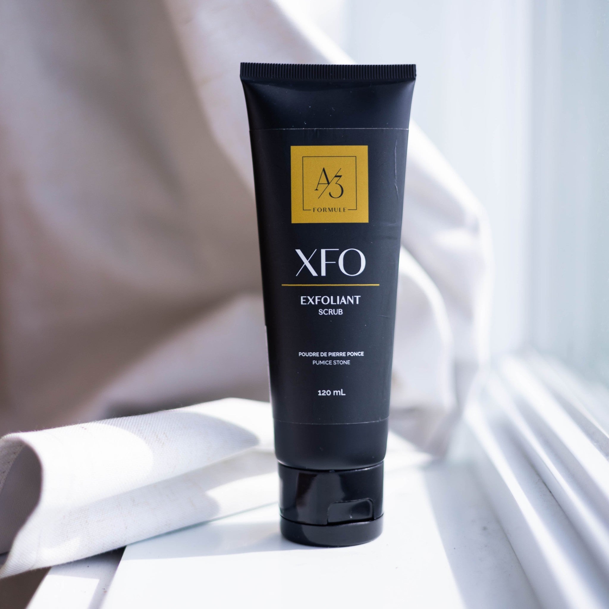 Black 120 ml tube of XFO exfoliant scrub by Formule A3 on a white windowsill
